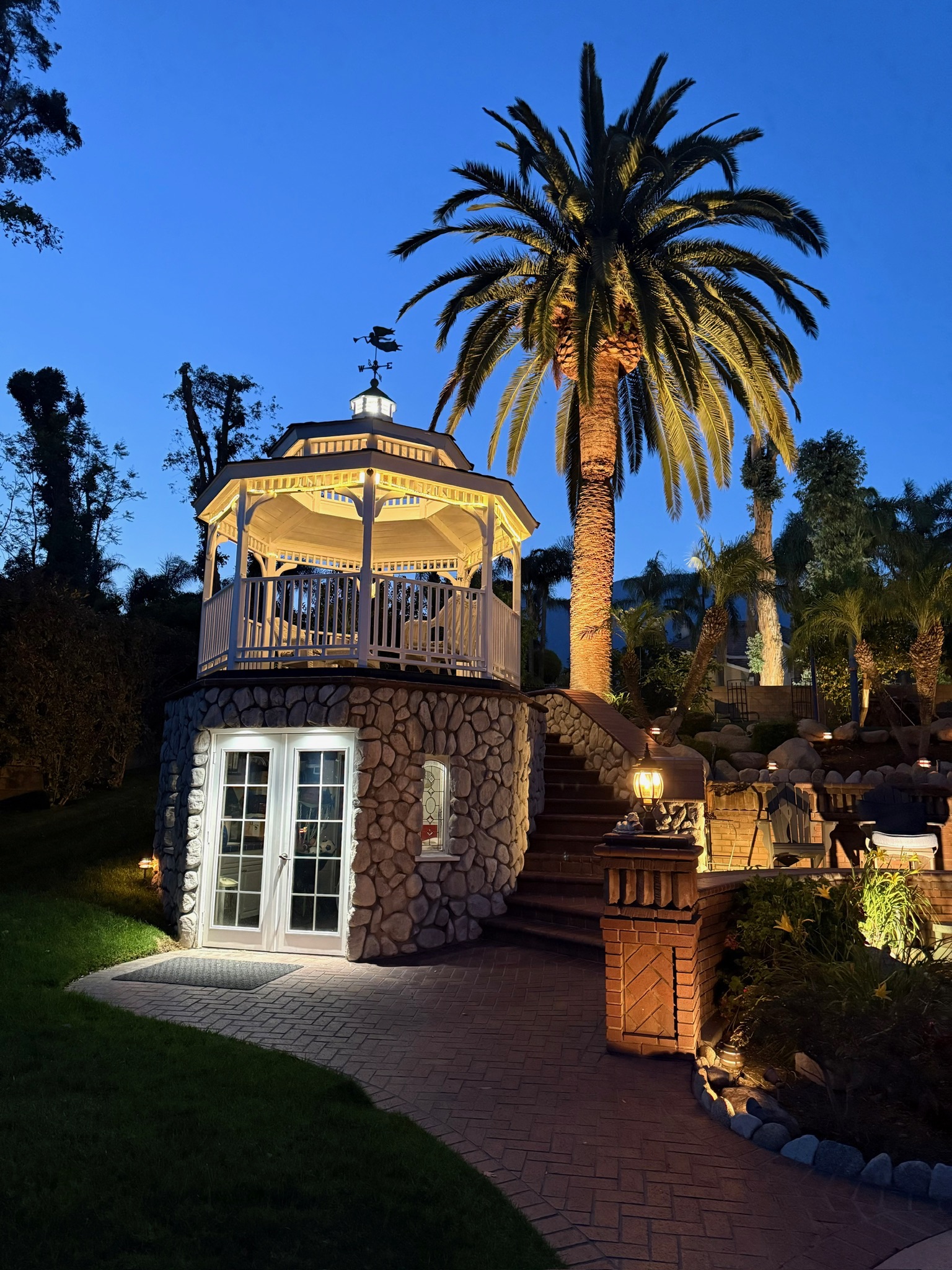White gazebo with weathervane and wicker furniture