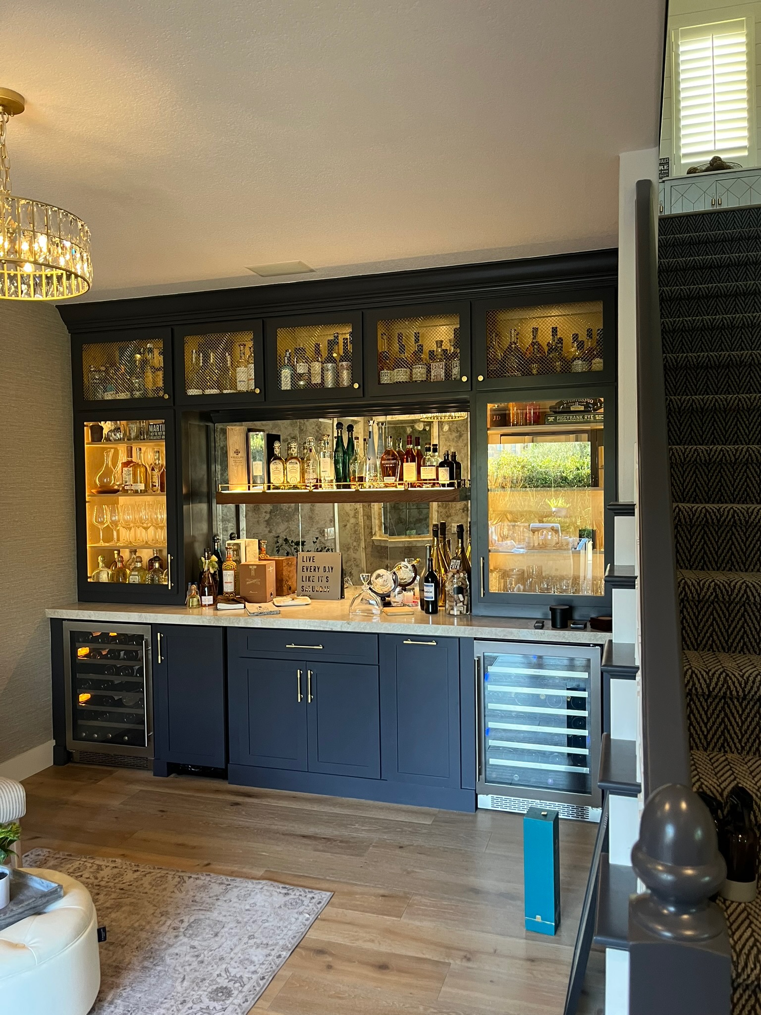 Navy blue home bar with crystal chandelier and wine fridges